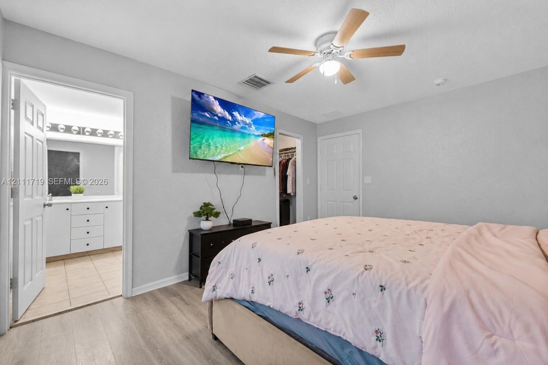 Wood-finish flooring, ceiling fan with integrated lighting, and multiple interior paneled doors
