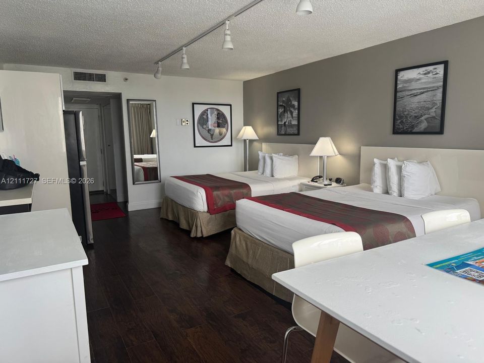 Spacious room featuring wood-finish flooring, track lighting, and a neutral color palette