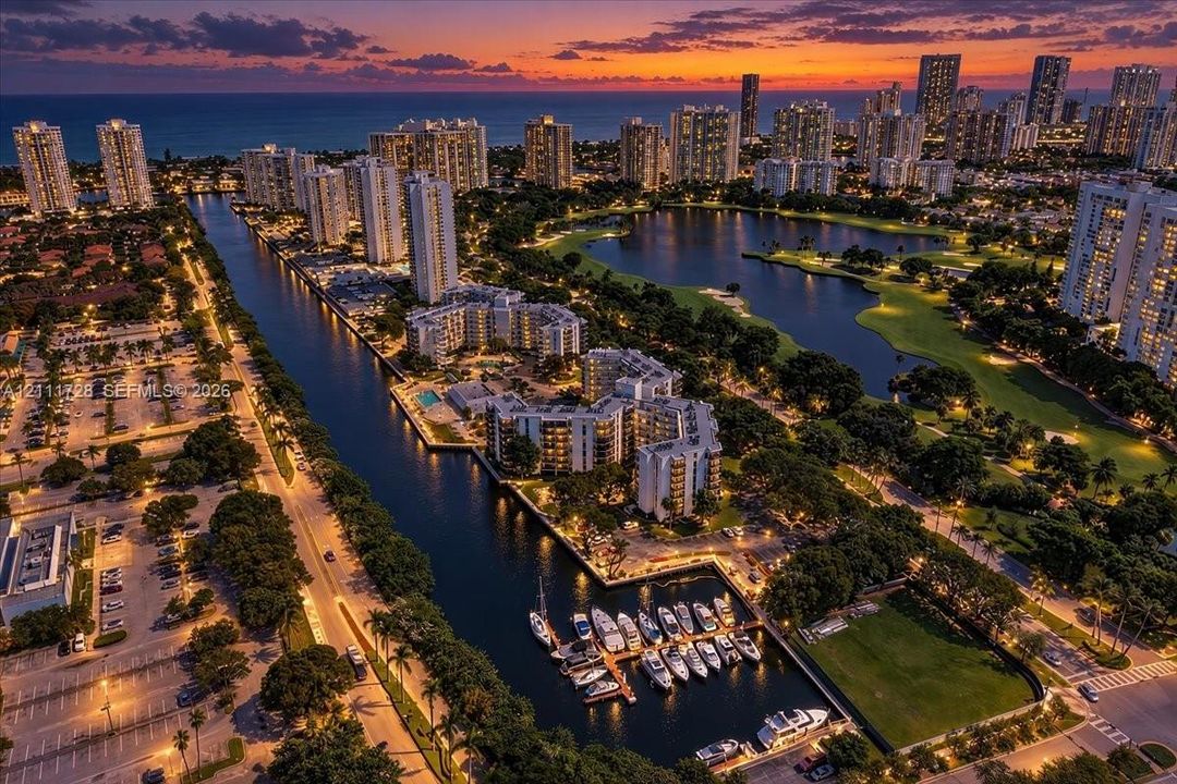 Aerial perspective of a coastal waterfront community featuring deep-water canal access, private boat slips, multi-level residential structures, and landscaped green space