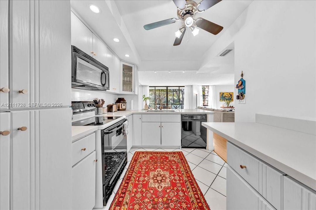 Kitchen featuring white cabinetry, solid surface countertops, recessed lighting, tile flooring, and built-in appliances