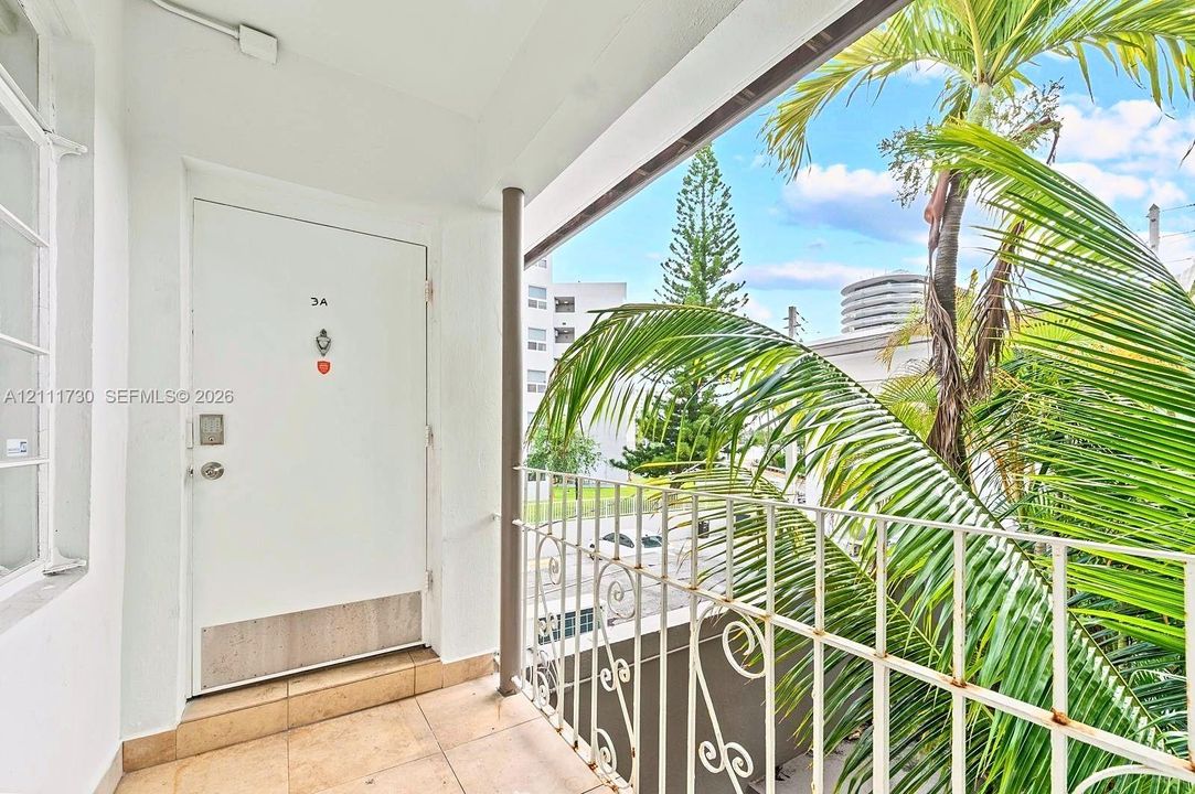 Covered entryway featuring large-format tile flooring and a decorative white metal railing