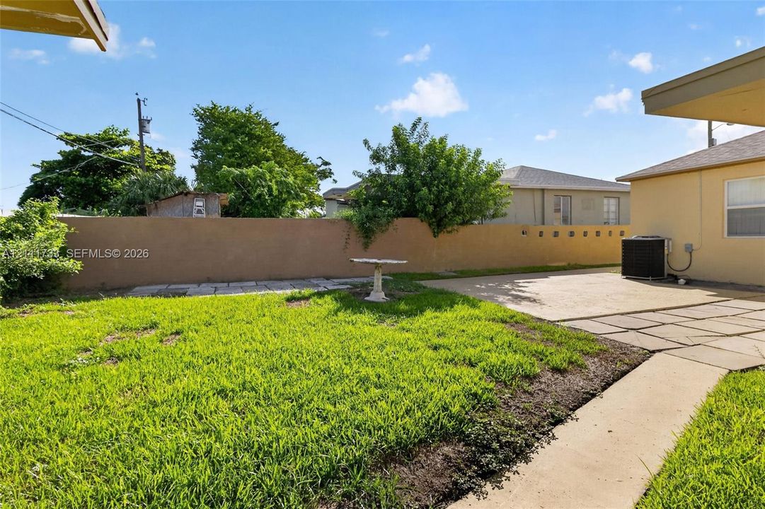 Backyard featuring a concrete patio, sod lawn, and a perimeter masonry wall.