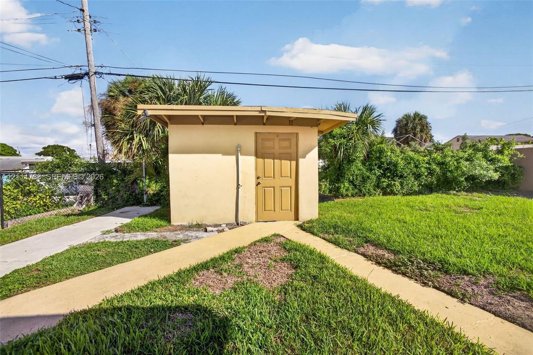 Exterior storage structure featuring  a single-entry door and concrete walkway.