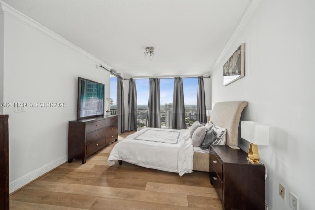 Floor-to-ceiling windows, wood-finish flooring, and crown molding