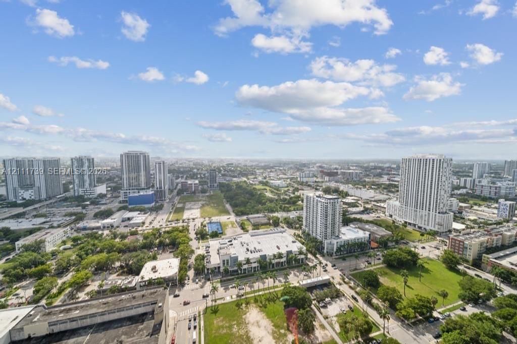 Elevated perspective of the surrounding metropolitan landscape, featuring high-rise architecture, mixed-use developments, and expansive green spaces