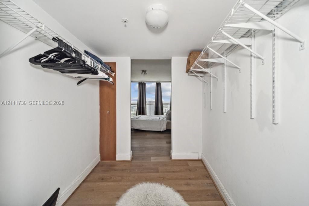 Walk-in closet featuring white wire shelving, wood-finish flooring, and a flush-mount ceiling light fixture