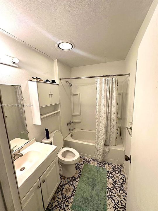 Bathroom featuring patterned tile flooring, vanity with integrated sink, wall-mounted cabinetry, and a tub-shower combination with recessed shelving