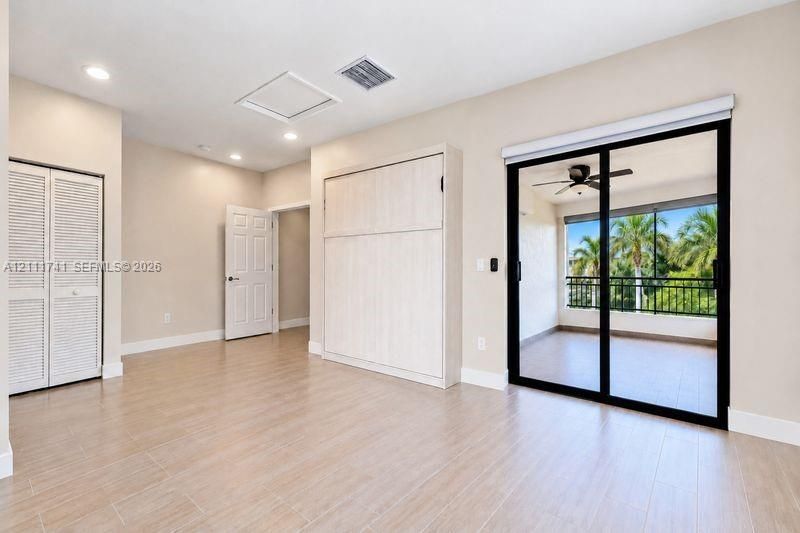 Room featuring wood-finish tile flooring, built-in cabinetry, recessed lighting, and a large sliding glass door with access to a railed balcony