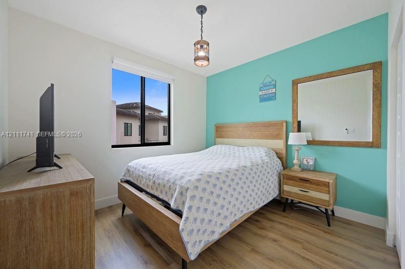 Room featuring wood-finish flooring, a single-light pendant fixture, and an accent wall