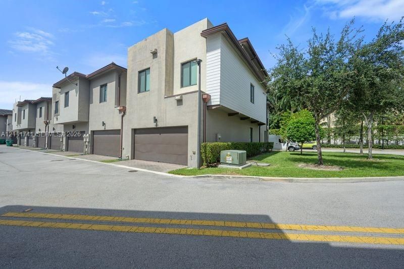 Multi-story exterior featuring a textured stucco facade, horizontal lap siding, attached multi-car garages, and manicured landscaping