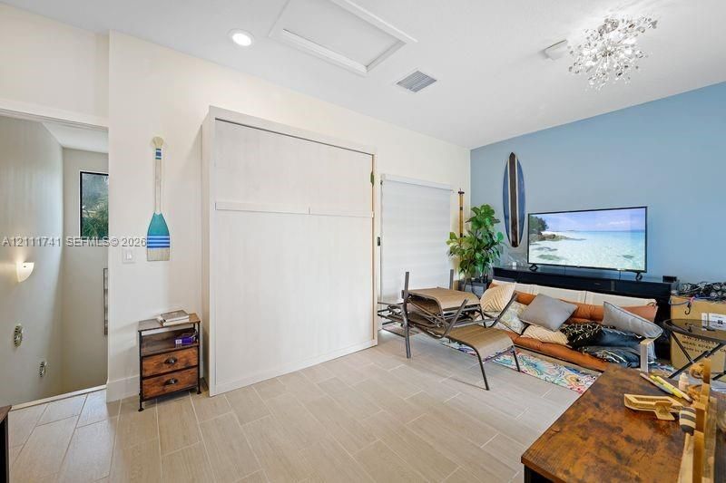 Multi-purpose room featuring wood-finish tile flooring, a built-in wall unit, recessed lighting, and a crystal-style chandelier