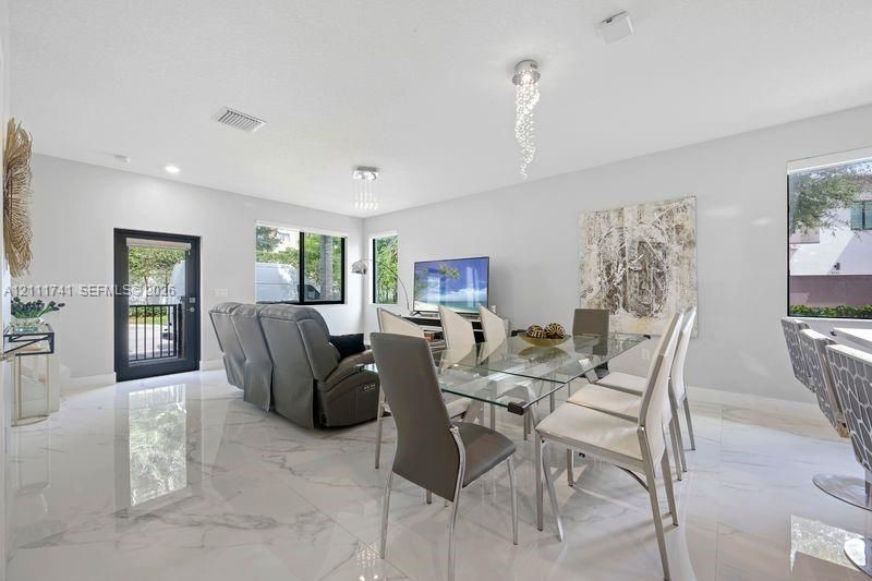 Large-format polished tile flooring, dual contemporary crystal pendant light fixtures, and expansive windows with black frames