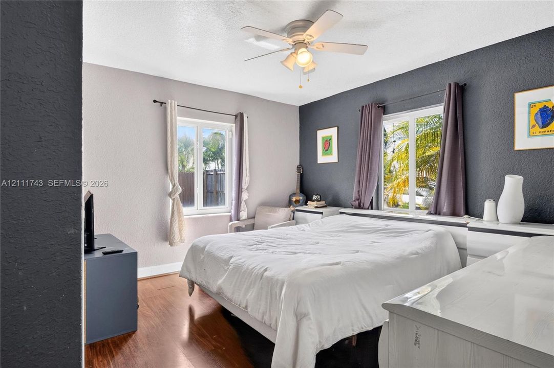 Wood-finish flooring, dual-tone painted walls, and ceiling-mounted light fixture with fan