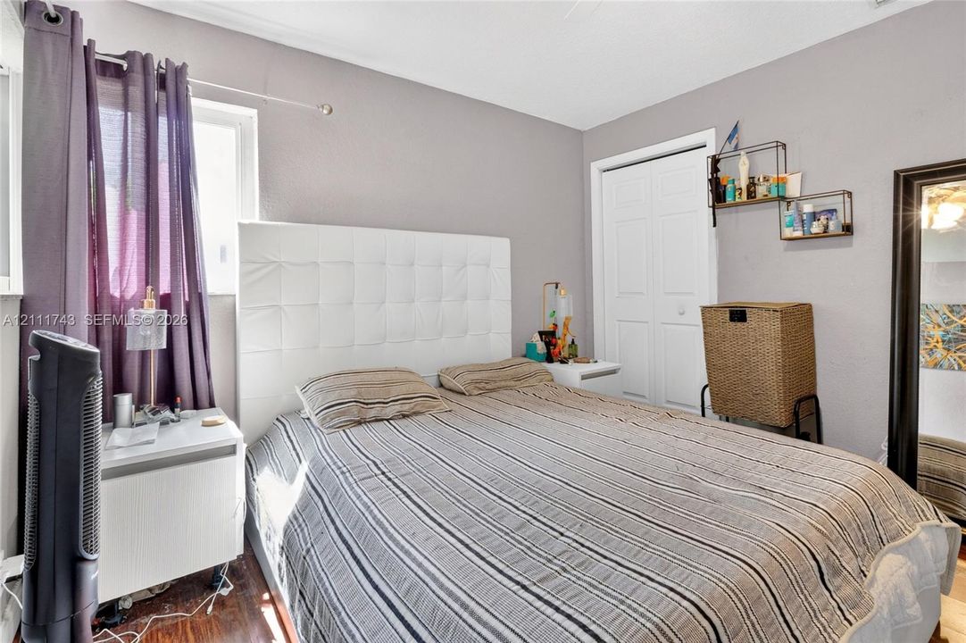 Wood-finish flooring, white bifold closet doors, and wall-mounted shelving