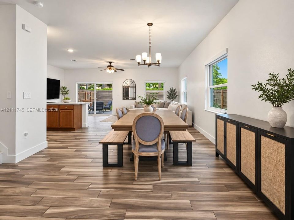 Open-concept interior featuring wood-finish tile flooring, a multi-light chandelier, sliding glass doors, and a kitchen island with stone countertops