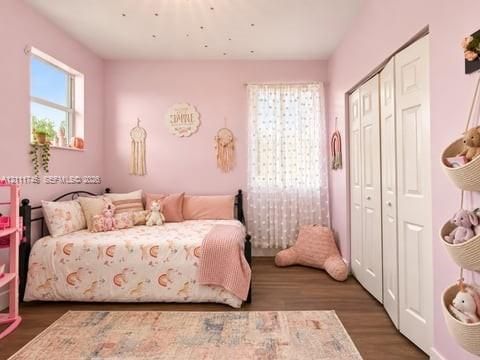 Bedroom featuring wood-finish flooring, dual windows, and bi-fold closet doors