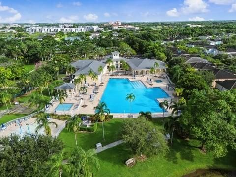 Resort-style aquatic complex featuring a large swimming pool, separate lap pool, integrated splash pad, and surrounding paved sun deck