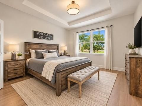 Room featuring a tray ceiling, wood-finish flooring, and a central drum pendant light fixture