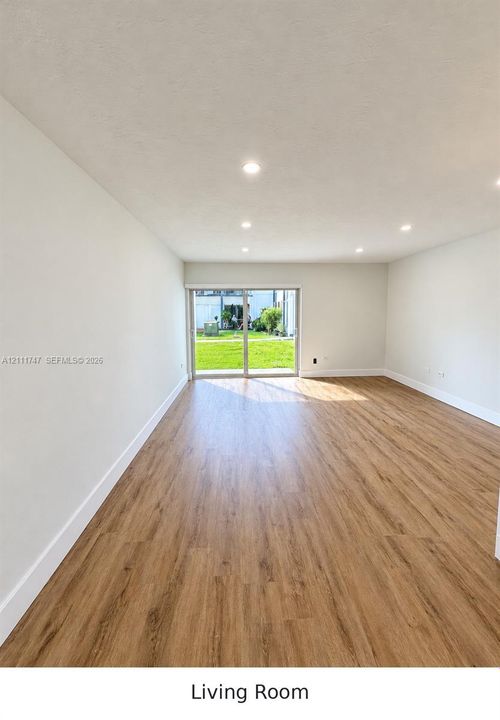 Open-concept interior featuring wood-finish flooring, recessed lighting, and sliding glass doors with access to a rear yard
