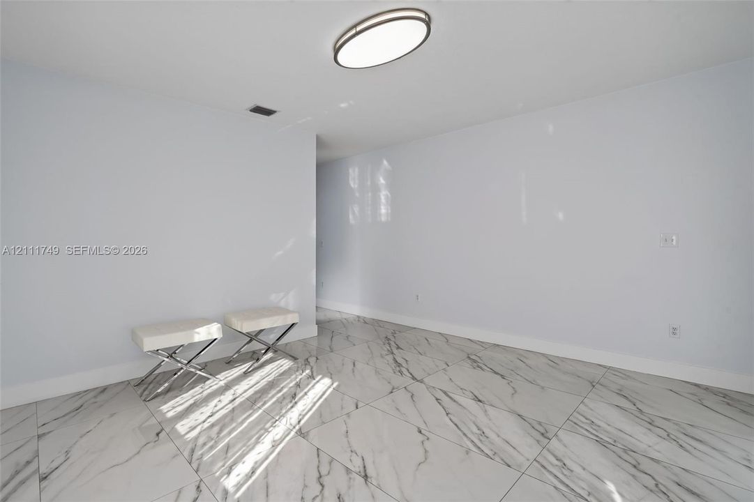 Large-format stone-style tile flooring with veining detail, crisp white wall finishes, and a contemporary oval flush-mount ceiling fixture
