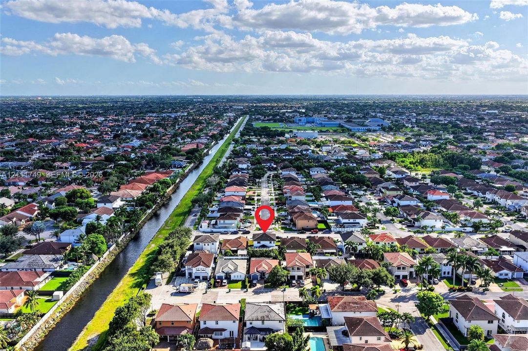 Aerial perspective of residential property situated in a suburban community, featuring a multi-pitched roofline and proximity to a canal