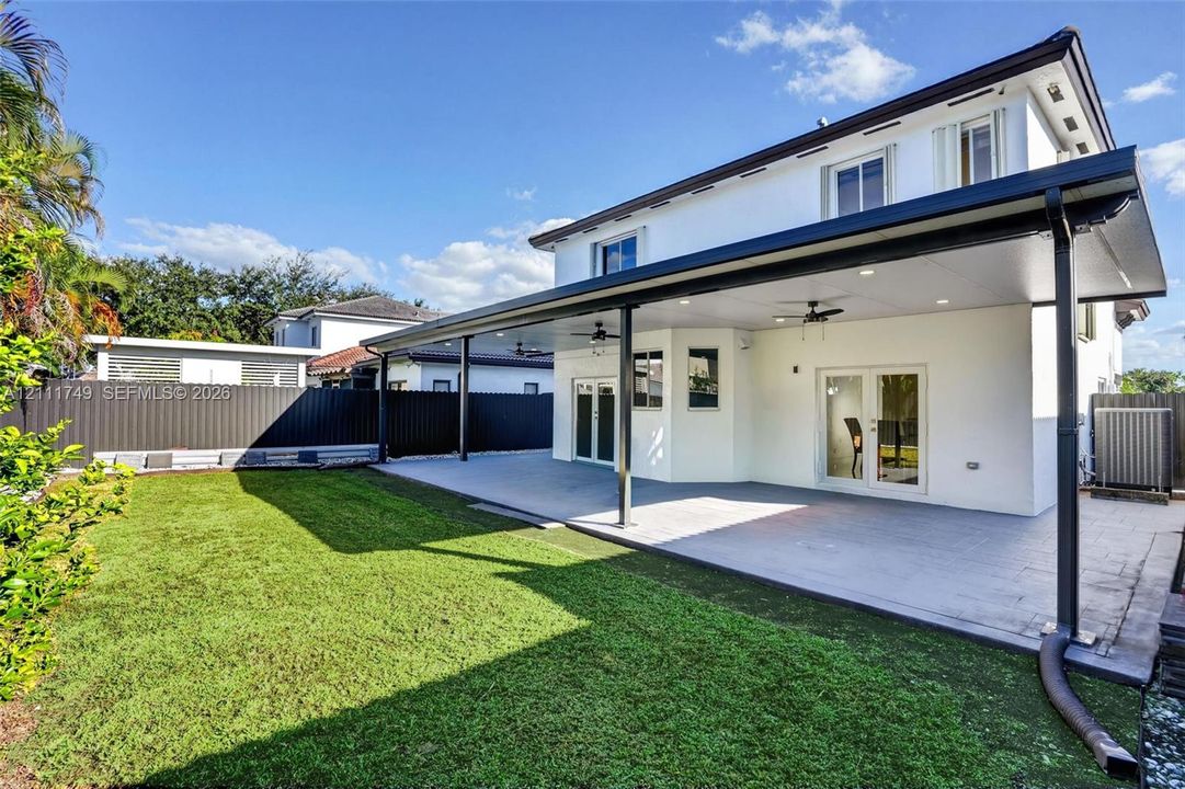 Two-story exterior featuring a stucco facade, covered rear patio with recessed lighting and ceiling fans, tiled flooring, and a fenced backyard