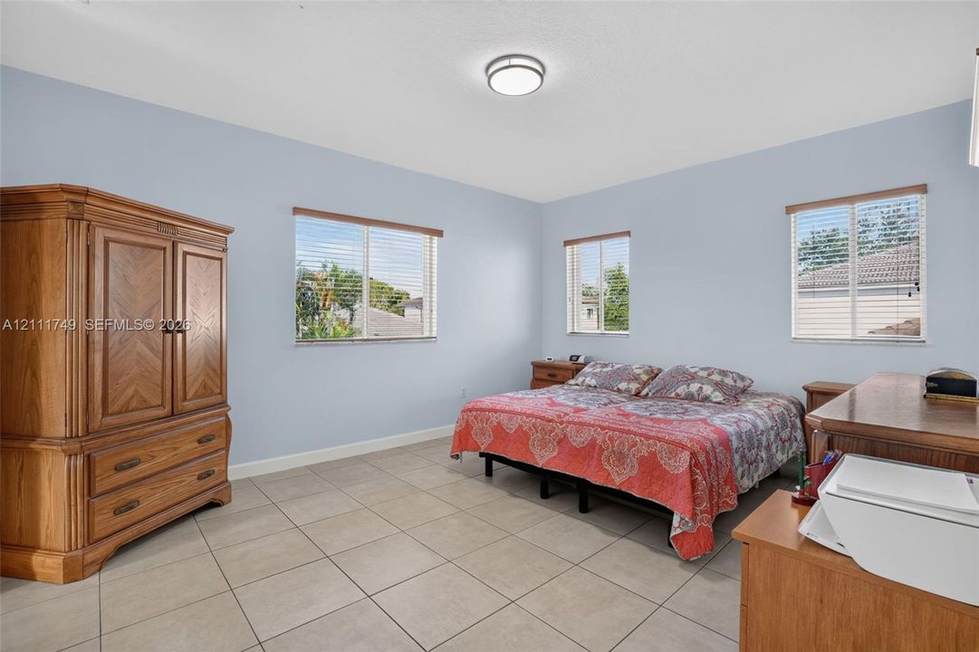 Neutral wall finishes, large-format tile flooring, flush-mount lighting, and triple windows with horizontal blinds