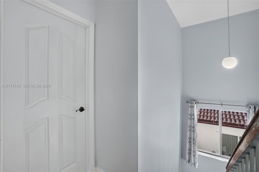 Four-panel interior door featuring a matte black lever handle, high ceiling, and globe pendant light fixture