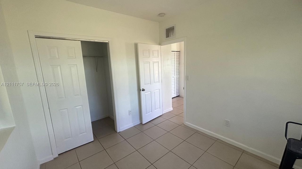 Neutral-toned ceramic tile flooring, solid-core six-panel interior doors, and built-in closet with sliding panel doors