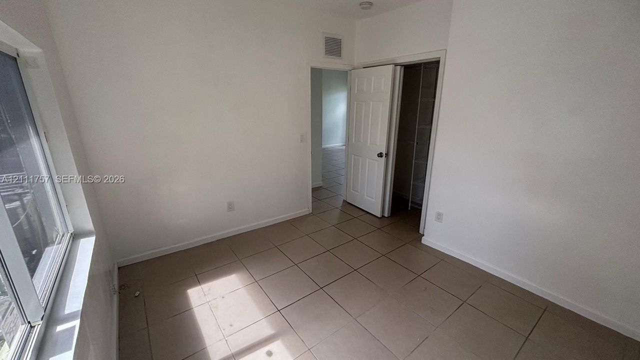 Neutral-toned ceramic tile flooring, multi-pane window, and six-panel interior door