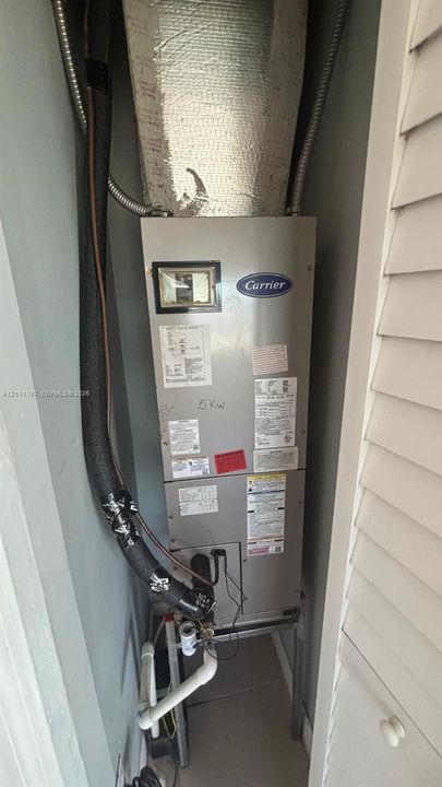 Carrier HVAC air handler unit featuring insulated refrigerant lines and PVC drain piping