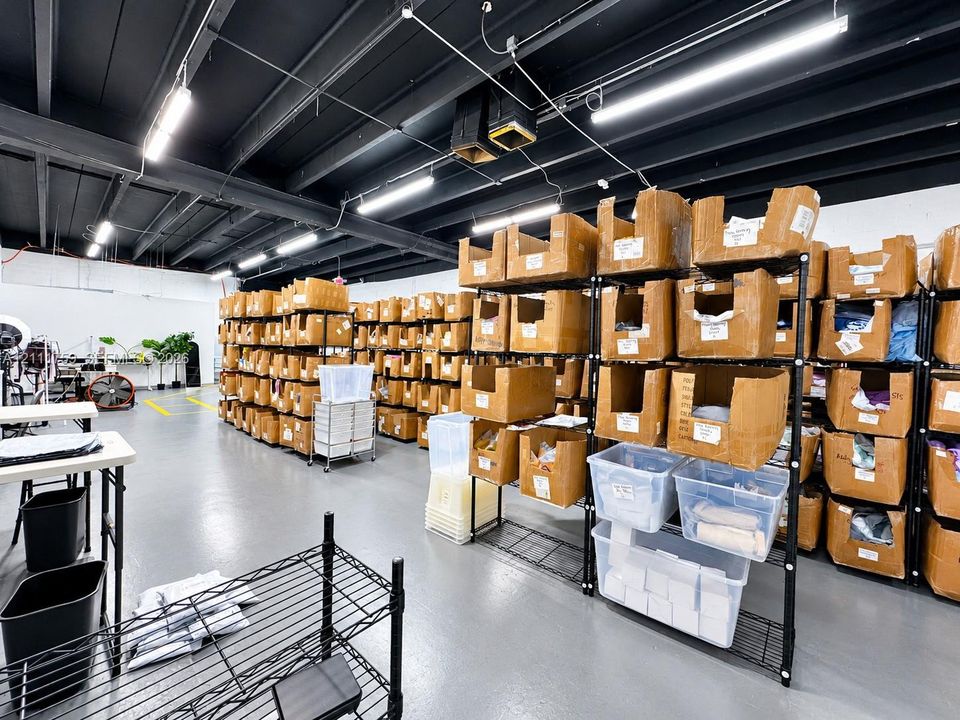 Industrial-style workspace featuring an expansive open floor plan, exposed dark-toned ceiling joists, durable floor coating, and high-output linear lighting