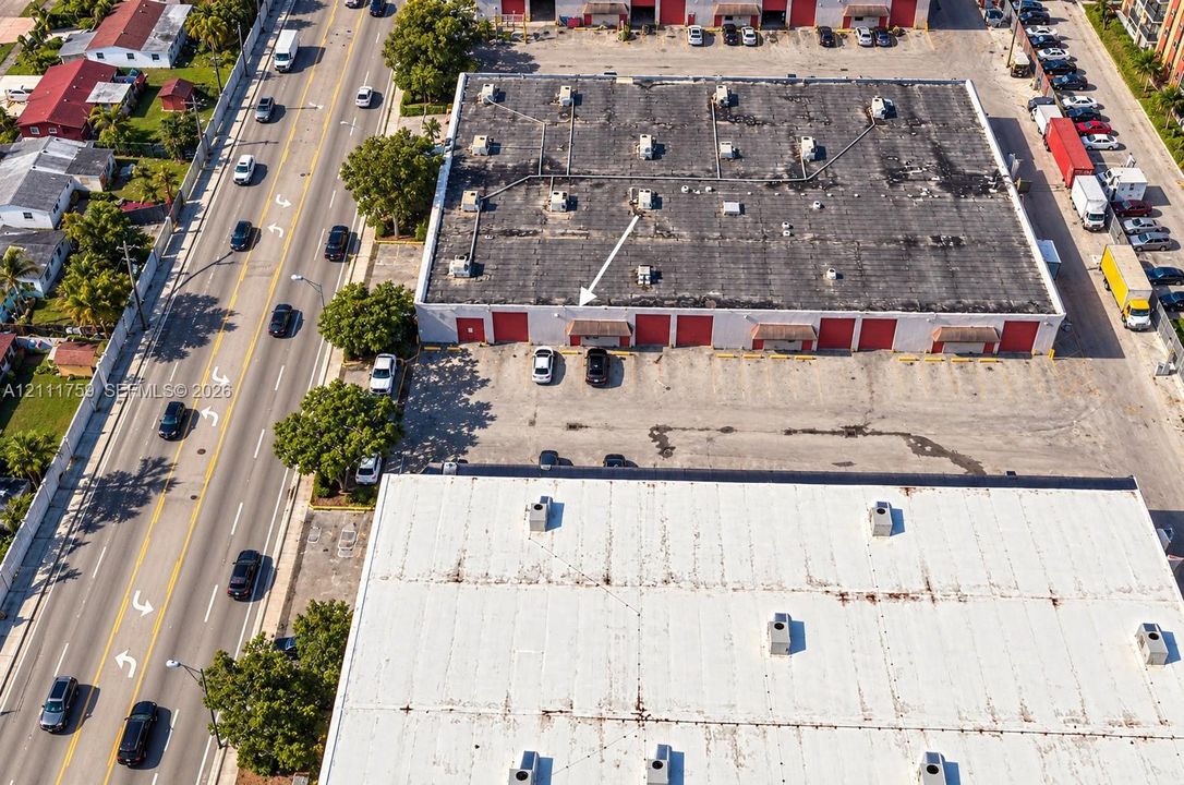 Industrial property featuring direct frontage on a high-traffic thoroughfare, multiple roll-up bay doors, and an expansive asphalt parking lot