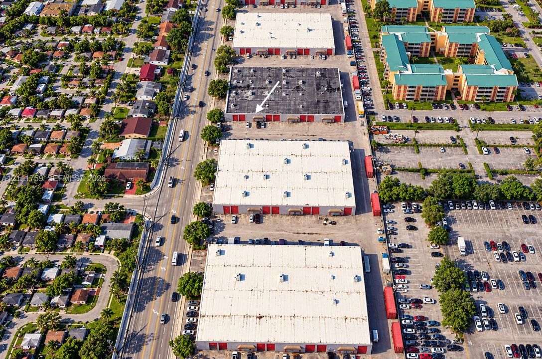 Aerial perspective of industrial warehouse complex featuring paved parking areas, multi-bay loading access, flat roof systems, and proximity to major roadway infrastructure