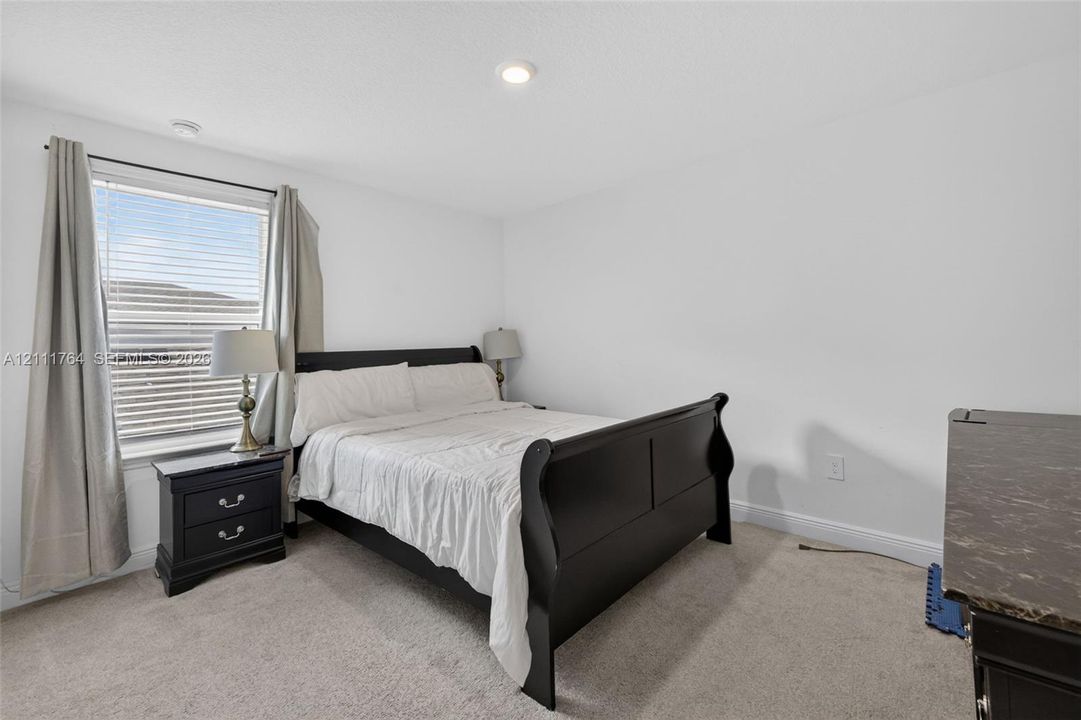 Bedroom featuring neutral wall-to-wall carpeting, recessed ceiling lighting, and a window with horizontal blinds