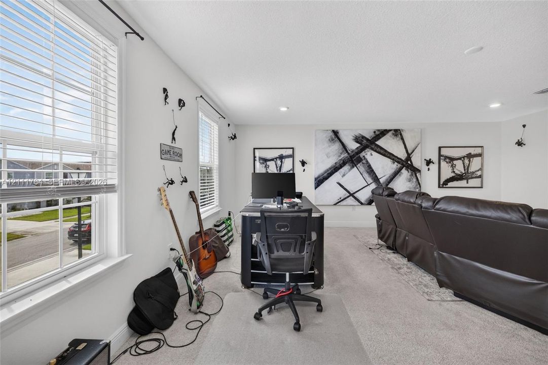 Spacious interior featuring neutral wall tones, recessed lighting, carpeted flooring, and multi-pane windows with horizontal blinds