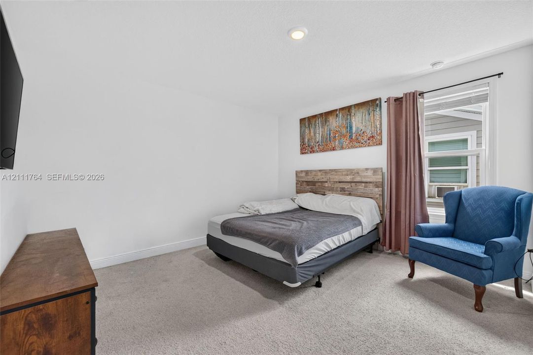 Neutral-toned wall-to-wall carpeting, recessed ceiling lighting, and a window with trim framing