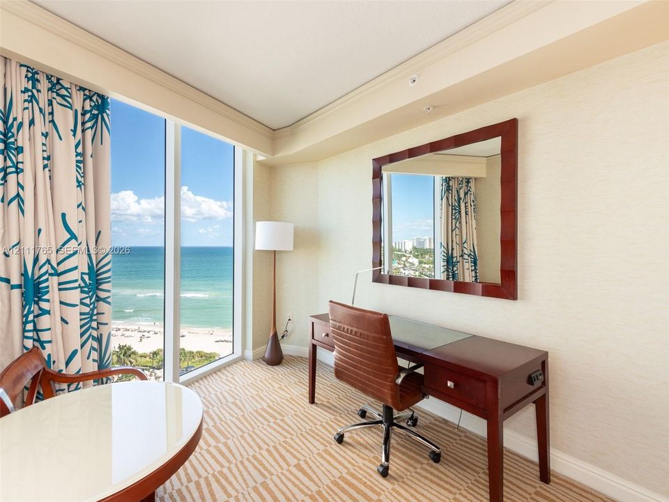 Floor-to-ceiling windows featuring ocean scenery, textured wall surfaces, and crown molding