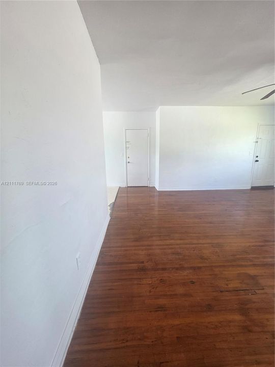 Interior space featuring wood-finish flooring, white walls, two interior doors, and a ceiling-mounted fan