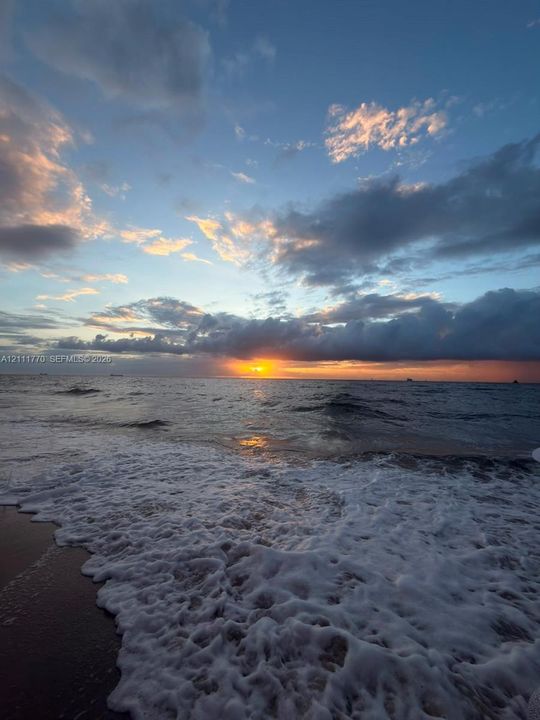 Oceanfront setting featuring direct water access, sandy beach terrain, and a horizon sunset