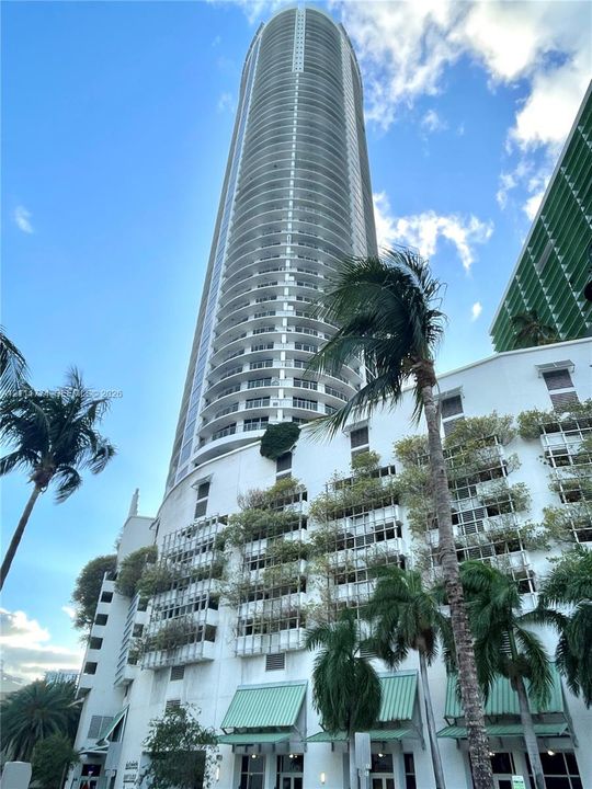 High-rise building featuring rounded structural design, continuous wraparound balconies, white facade, and integrated vertical landscaping