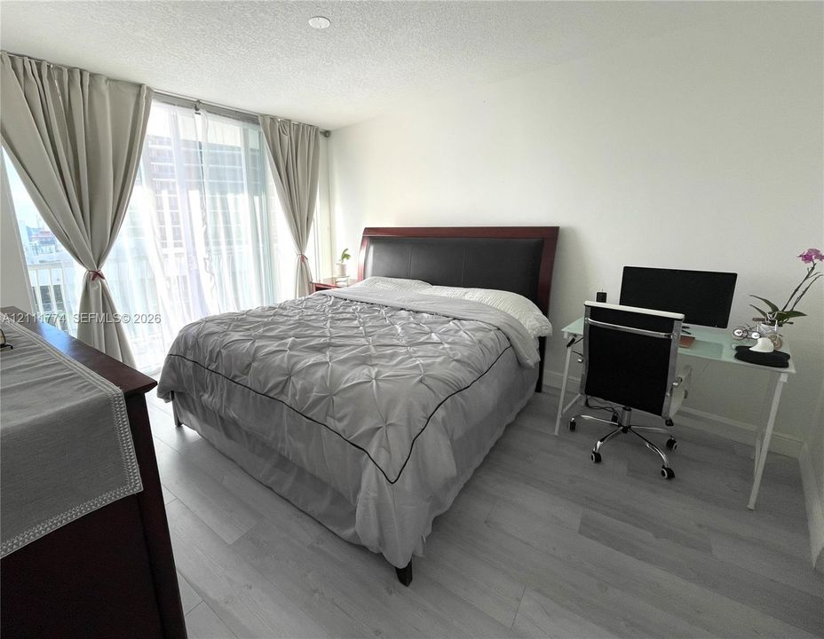 Floor-to-ceiling sliding glass door with dual curtain panels and wood-finish flooring
