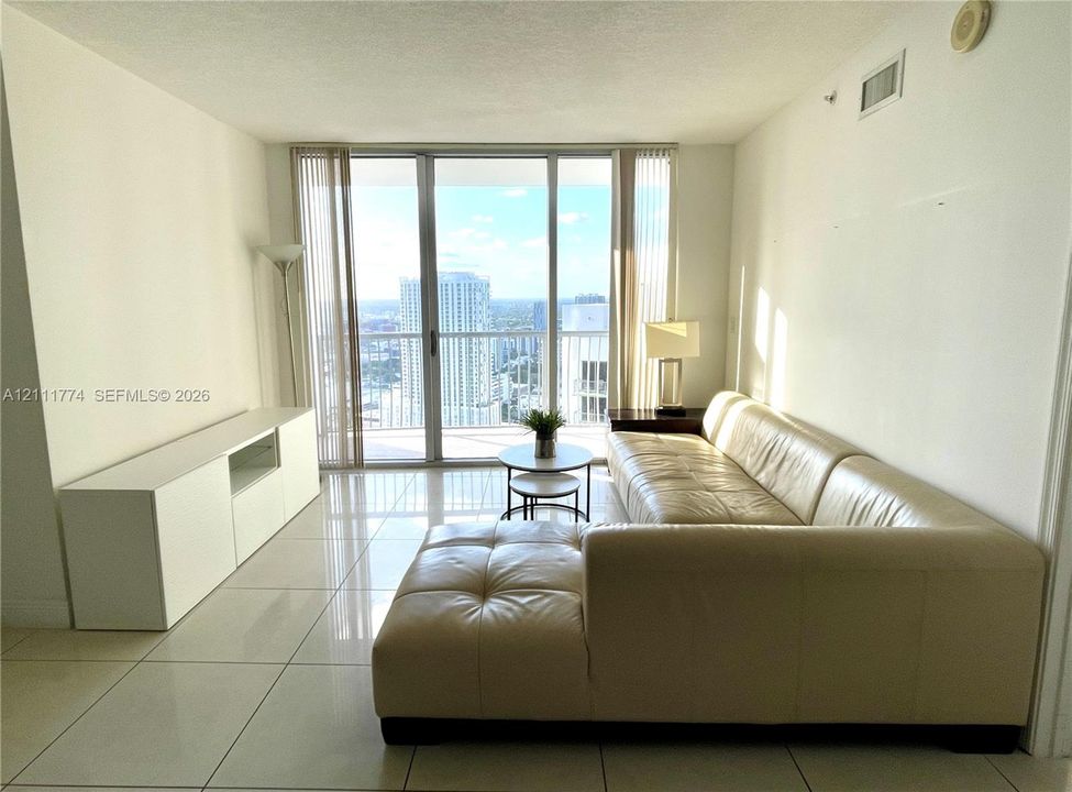 Full-height sliding glass doors with access to a private balcony, complemented by polished tile flooring throughout