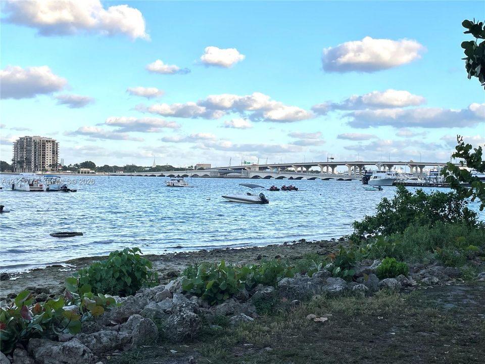 Waterfront property featuring a stone-lined shoreline, grass area, and foliage