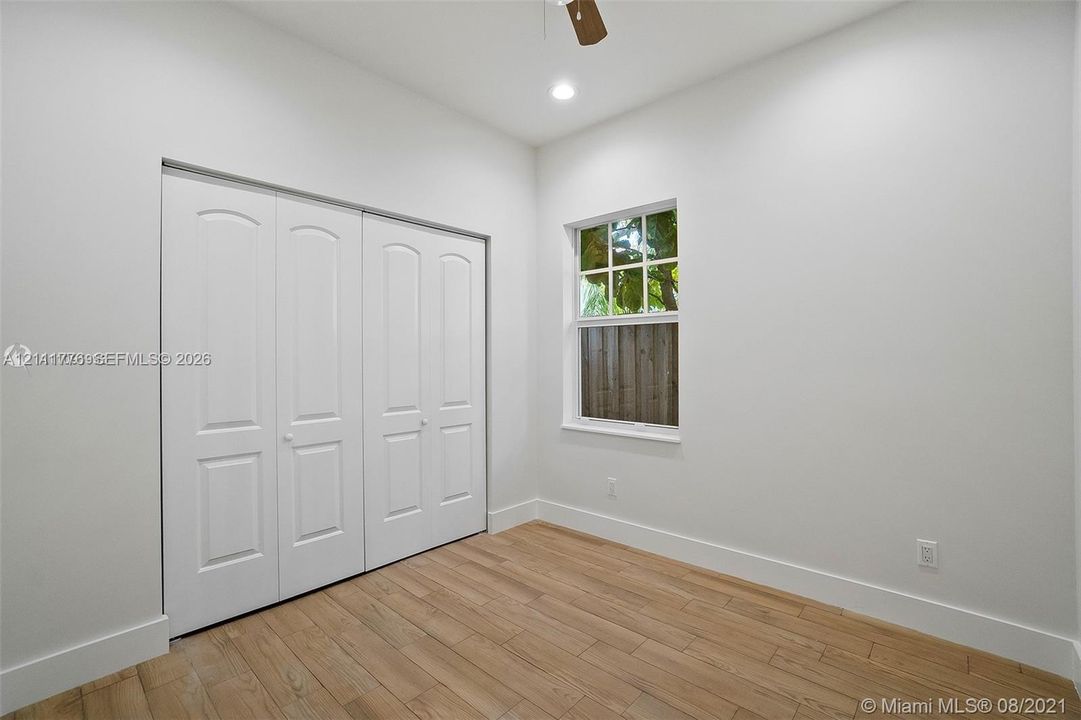 Wood-finish flooring, multi-panel closet doors, recessed lighting, ceiling fan, and multi-pane window