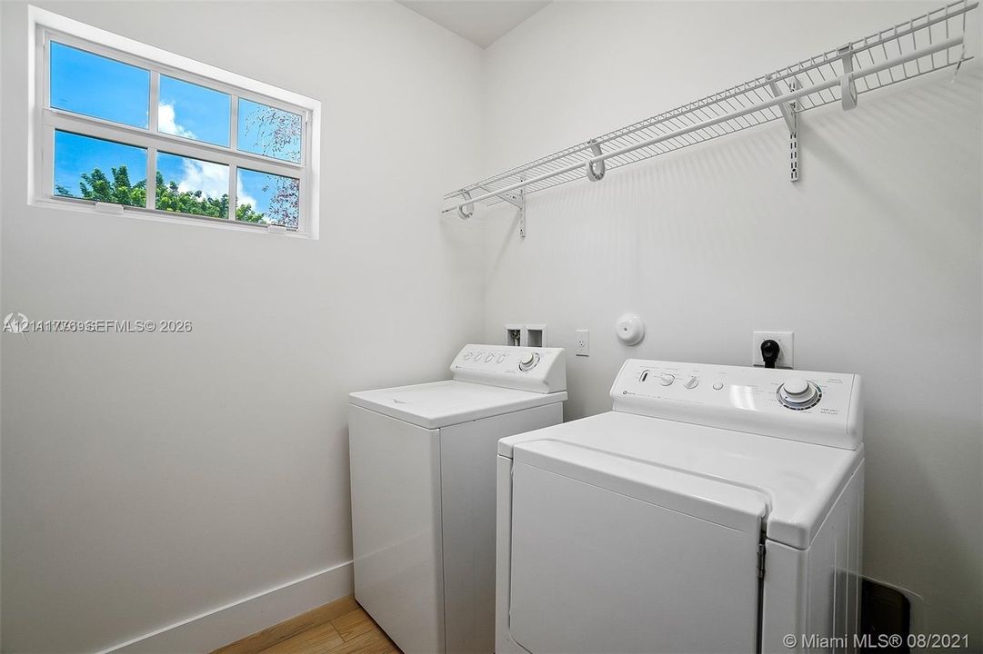 Laundry area featuring wood-finish flooring, a rectangular window, and wall-mounted wire shelving