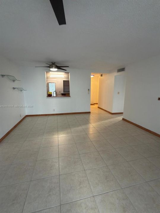 Interior space featuring neutral tile flooring, ceiling-mounted fan, and wall-mounted glass display shelving