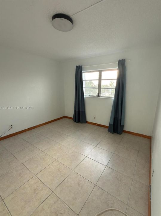 Room featuring neutral ceramic tile flooring, a horizontal multi-pane window, and a circular flush-mount ceiling light
