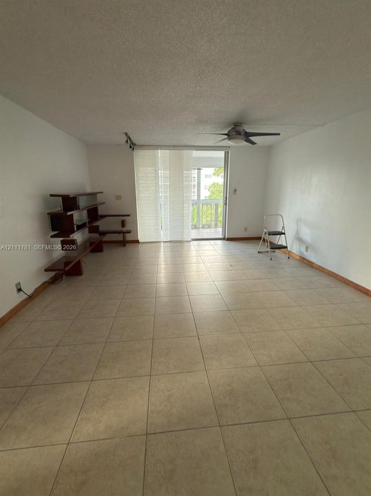 Neutral-toned ceramic tile flooring, ceiling-mounted fan, and glass sliding doors leading to an exterior balcony