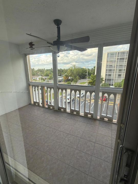 Enclosed balcony featuring tile flooring, decorative arched railings, and a ceiling fan